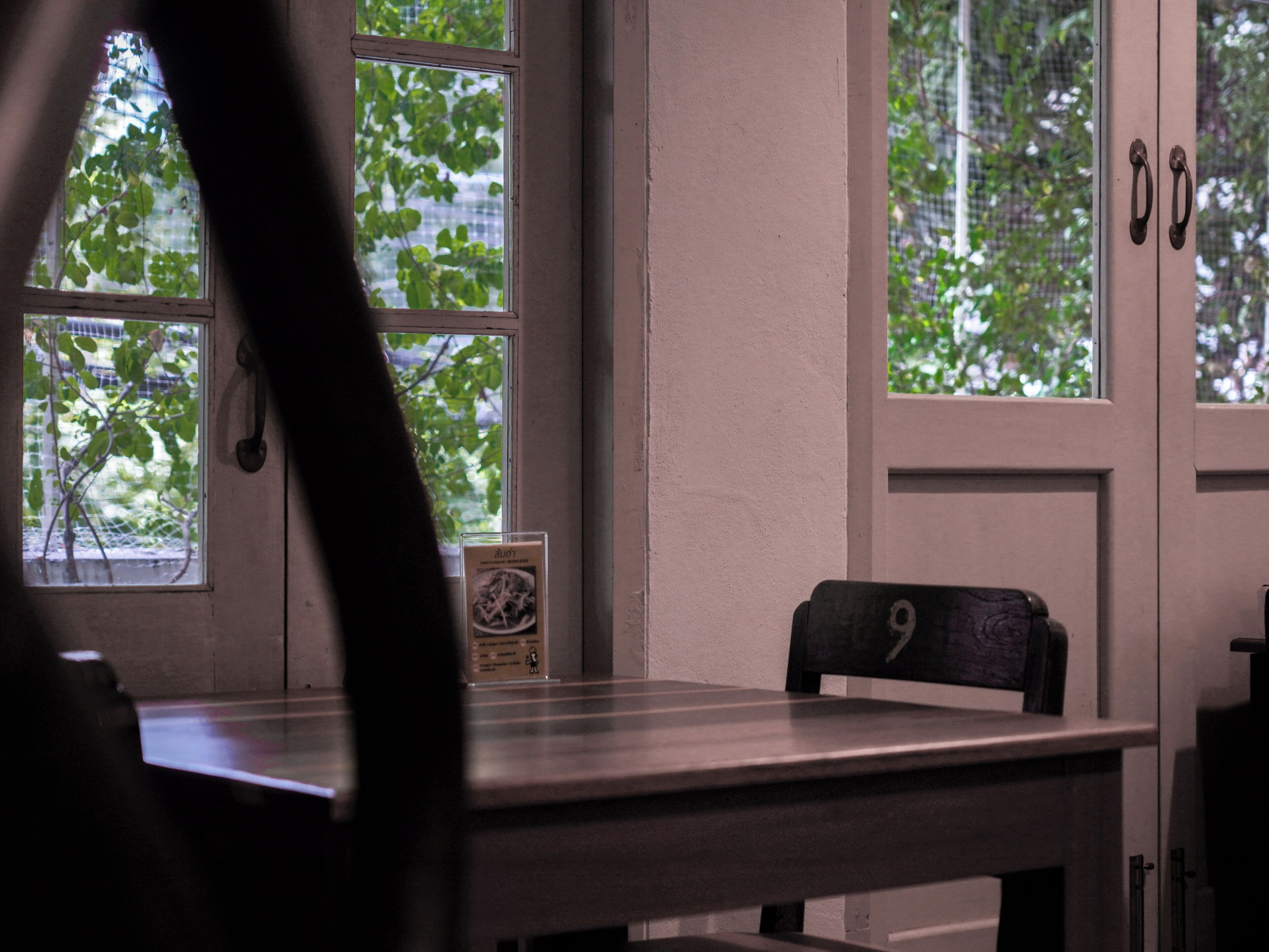 Una habitación con una mesa, una silla y una ventana que da a árboles.