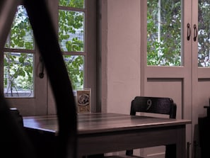 Une pièce avec une table, une chaise et une fenêtre donnant sur des arbres.