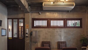 A reception area with a wooden door, a small table, two chairs, and a potted plant. - Niagara Hotel (Bangkok)