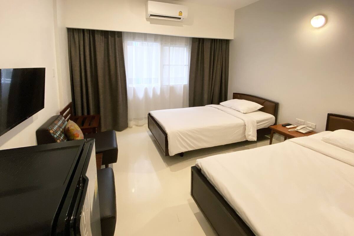 A hotel room with two beds, a TV, a desk, and a phone.