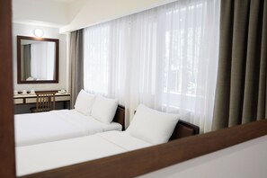 A hotel room with two beds, a desk with a telephone, and a mirror. - Niagara Hotel (Bangkok)