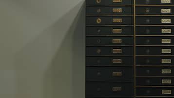 Uma fileira de armários de arquivo pretos com etiquetas numeradas, uma escrivaninha de madeira e uma cadeira vermelha.