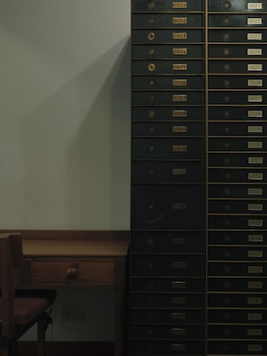 A row of black filing cabinets with numbered labels, a wooden desk, and a red chair. - Niagara Hotel (Bangkok)