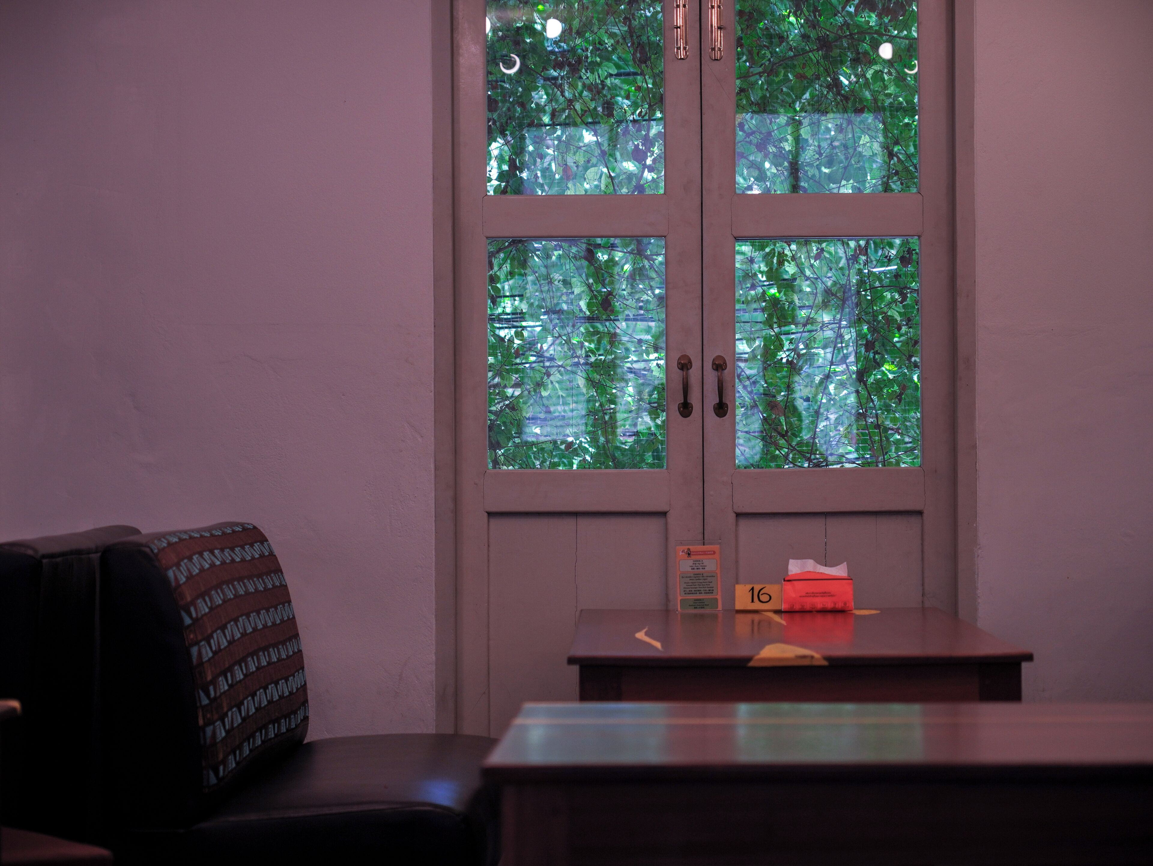 Une pièce avec une porte donnant sur un balcon, une table avec un panneau et une chaise à motifs.
