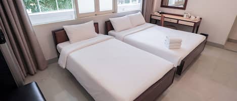 Habitación de hotel con dos camas, una mesita de noche con espejo y una ventana con cortinas.