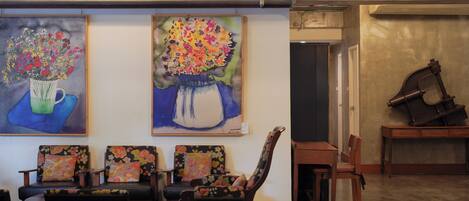 A lobby with a seating area, two paintings of flowers, and a clock on the wall.
