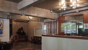A reception area with a wooden counter, a clock, and a seating area with chairs. - Niagara Hotel (Bangkok)