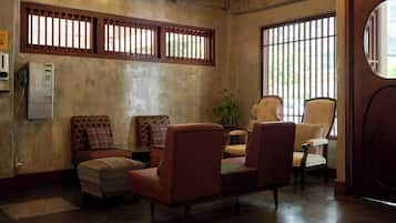 Una habitación con un sofá, sillones, una mesita y una planta en maceta.