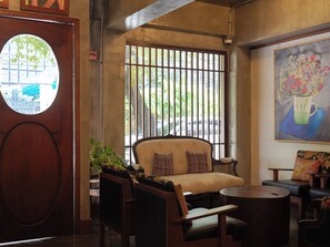 A room with a sofa, chairs, a small table, a painting, and a window with bars. - Niagara Hotel (Bangkok)
