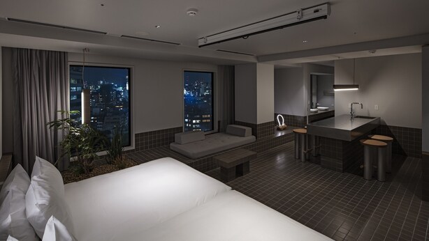 A modern hotel room with a large bed, a seating area, a bathroom with a sink and mirror, and a city view through large windows. - all day place shibuya (Tokyo)