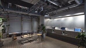 A modern reception area with a glass desk, seating, and potted plants.