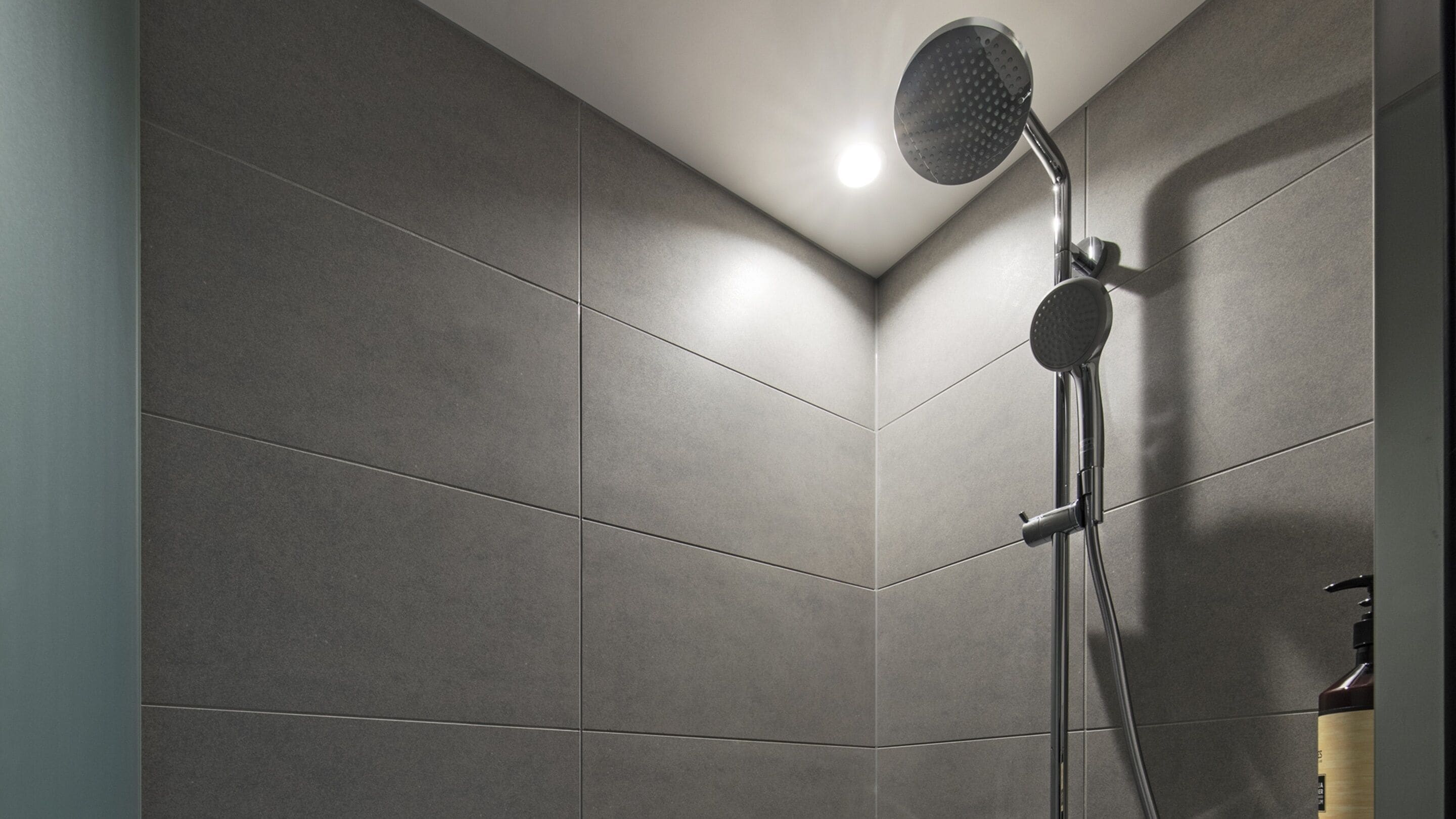 A shower area with a handheld showerhead mounted on a wall.