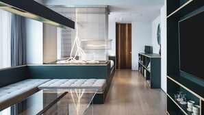A modern living room with a glass coffee table, a sofa, and a built-in bench. There is a wooden floor, a bookshelf, and a large window with blinds. - all day place shibuya (Tokyo)