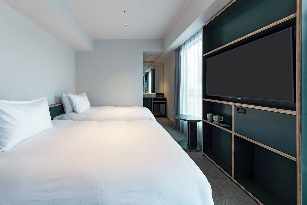 A hotel room with a large bed, a TV, and a desk with a chair.