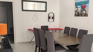 A dining area with a large wooden table, eight grey chairs, a red table, and a small mirror on the wall. - For family fun at the beach, at the center of everything that matters (Les Sables-d'Olonne)