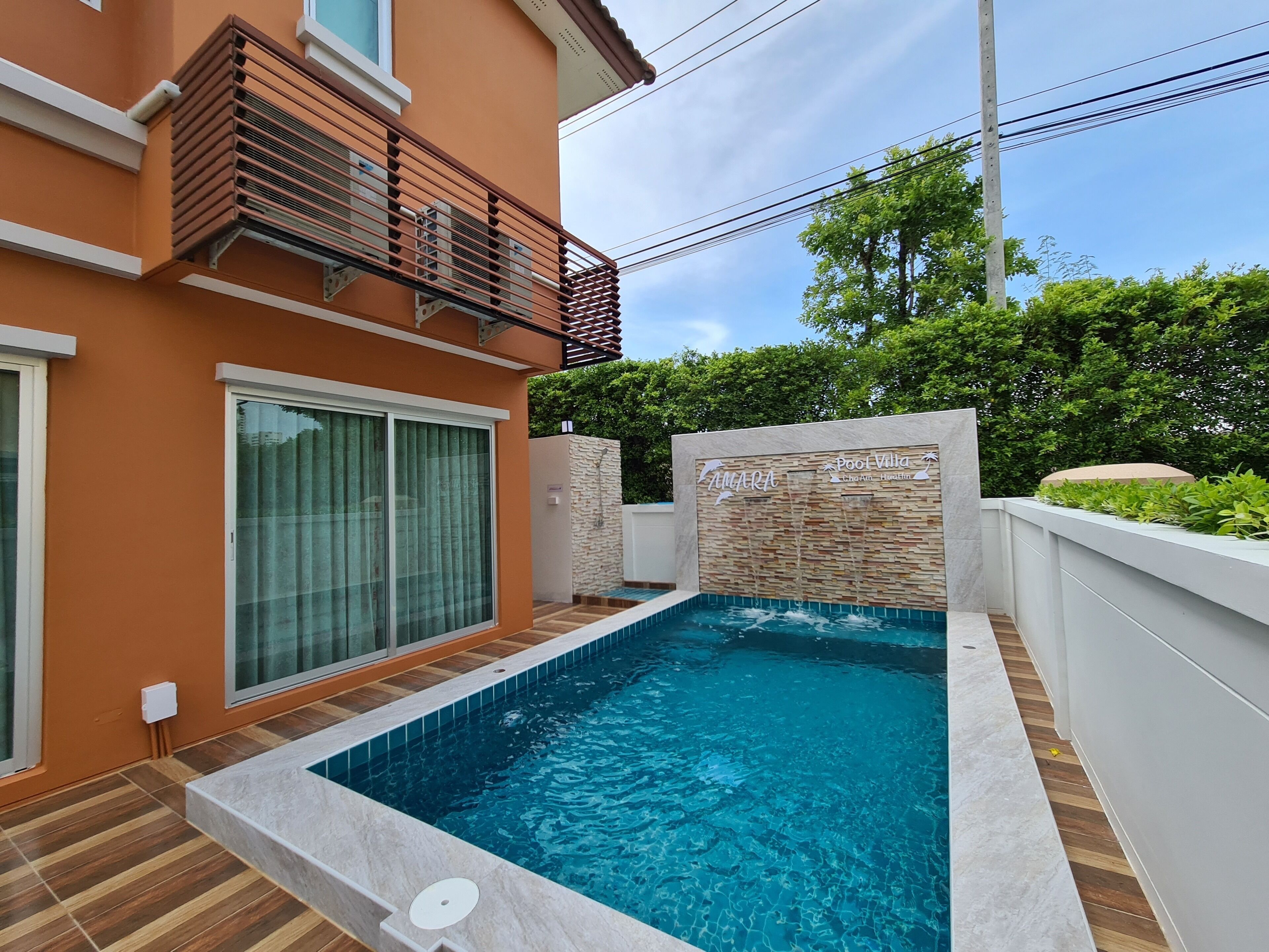 Una casa moderna con piscina, un balcone e un muro in pietra con segnaletica.