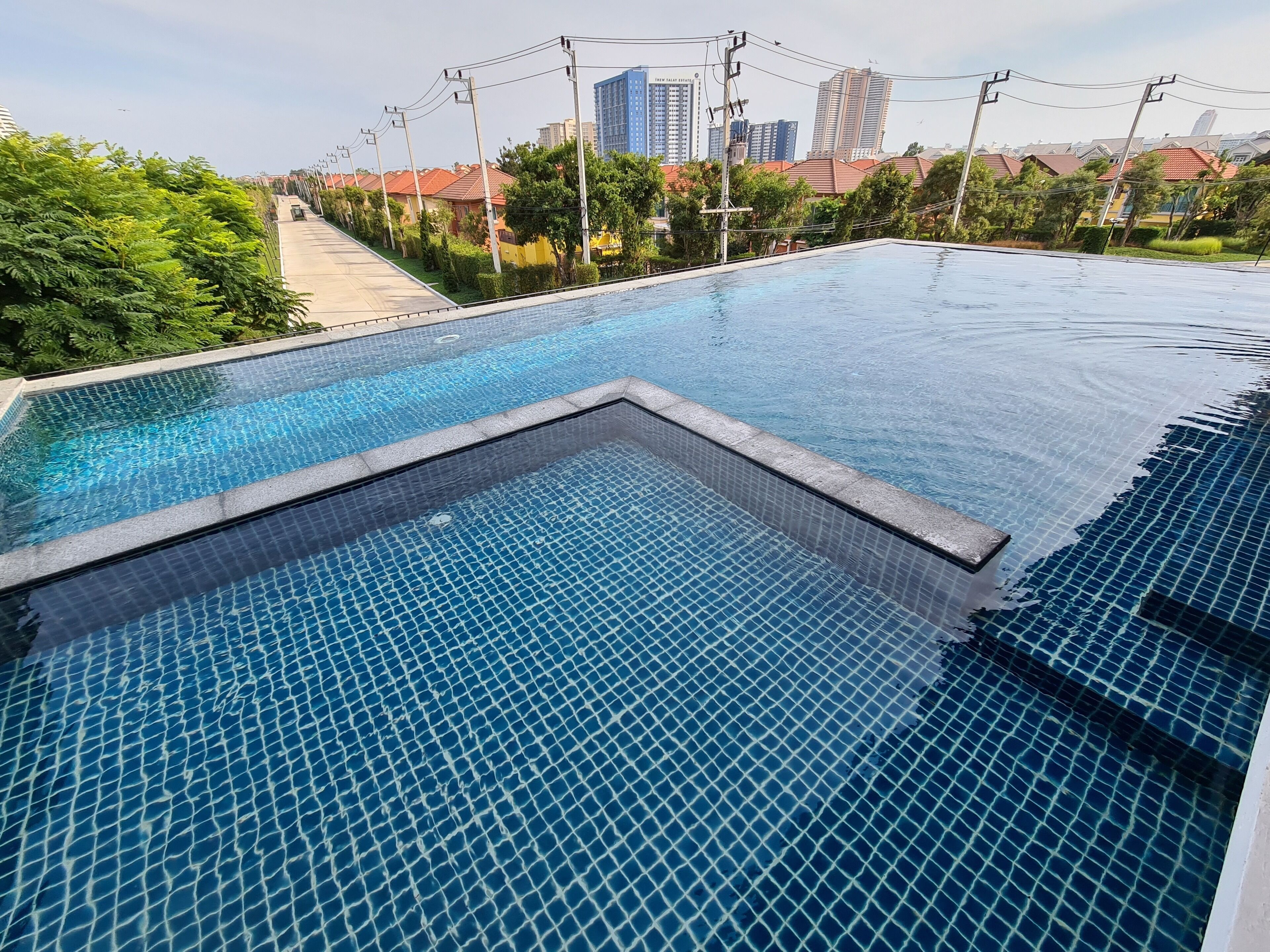A swimming pool with a tiled floor and a view of a cityscape in the background.