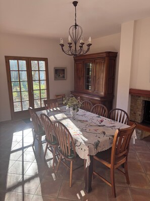 A dining room with a table set for six, surrounded by chairs, a chandelier, a cabinet, and a fireplace. - Spacious, 5 bd room home in a beautiful country setting in the French Alps. (Saint-Martin-d'Uriage)