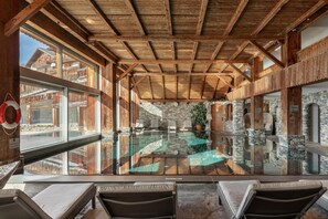 A pool area with wooden beams, stone walls, and lounge chairs. - Apartment Etrier Recently Renovated Crans-montana (Lens)