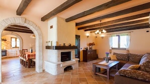 A spacious living area with a stone fireplace, wooden beams, a sofa, and a dining table. - Beautiful villa with pool for 8 near the beach (Tar-Vabriga)