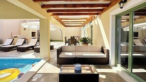 A poolside area with lounge chairs, a sofa, and a dining table. - Vacation home in Bale, perfect for families (Bale)