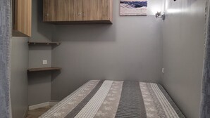 A small, narrow room with a bed, a wooden cabinet, and a mounted TV. - Renovated studio 4/5 ppl, south balcony, private parking, Pra Loup (Pra-Loup)