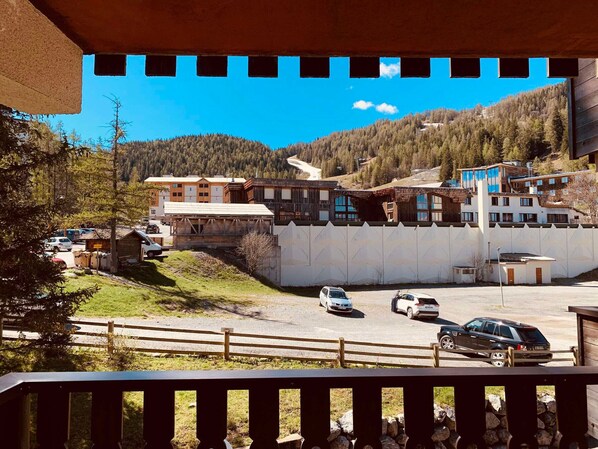 A hotel with a parking lot, a wooden fence, and a mountainous backdrop. - Renovated studio 4/5 ppl, south balcony, private parking, Pra Loup (Pra-Loup)