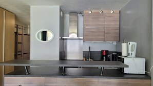 A modern kitchen with a central island, two bar stools, wooden cabinets, and a built-in oven. - Renovated studio 4/5 ppl, south balcony, private parking, Pra Loup (Pra-Loup)