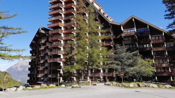 A multi-story hotel with balconies, a mountain view, and a ski slope in the background. - Renovated studio 4/5 ppl, south balcony, private parking, Pra Loup (Pra-Loup)