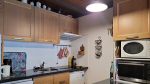 A modern kitchen with wooden cabinets, a Bosch dishwasher, a countertop with a coffee maker, and a microwave. - Cozy studio for 4 with sunny terrace in Pra-Loup (Pra-Loup)