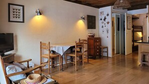 A cozy room with wooden furniture, a dining table, and a television. - Cozy studio for 4 with sunny terrace in Pra-Loup (Pra-Loup)