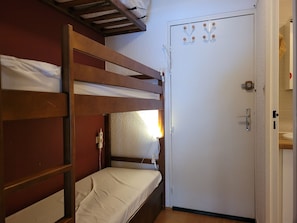 A bunk bed room with a wooden headboard, a white door with a handle, and a small window with a view of the outside. - Cozy studio for 4 with sunny terrace in Pra-Loup (Pra-Loup)