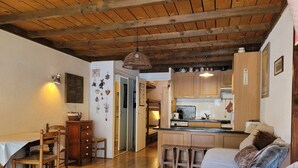 A cozy living room with a wooden ceiling, a dining area with a table and chairs, and a kitchen with wooden cabinets and a countertop. - Cozy studio for 4 with sunny terrace in Pra-Loup (Pra-Loup)