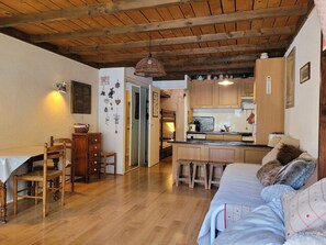 A cozy living room with a wooden ceiling, a dining area with a table and chairs, and a kitchen with wooden cabinets and a countertop. - Cozy studio for 4 with sunny terrace in Pra-Loup (Pra-Loup)