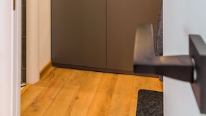 A hallway with a wooden floor and a grey wardrobe with two doors. - Studio 54 by MRG Apartments (Bucharest)