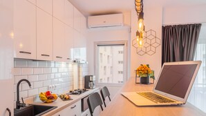 A modern kitchen with white cabinets, a black sink, and a laptop on the counter. - Studio 54 by MRG Apartments (Bucharest)