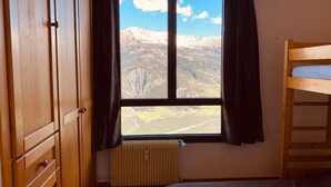 A room with a wooden wardrobe, a window with a mountain view, a radiator, and a bunk bed. - Beautiful renovated apartment with private parking in Pra Loup (Pra-Loup)