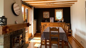 A cozy dining area with a wooden table, chairs, and a fireplace. - Spacious chalet in Pra Loup, 4 bedrooms, WiFi (Pra-Loup)