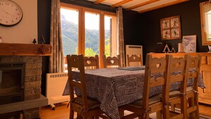 A cozy dining area with a stone fireplace, wooden chairs, and a table set for two. - Spacious chalet in Pra Loup, 4 bedrooms, WiFi (Pra-Loup)