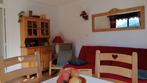Una sala de estar acogedora con una mesa de madera, un sofá rojo y un mueble de madera.