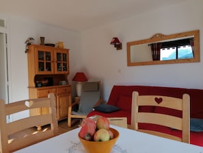 Una sala de estar acogedora con una mesa de madera, un sofá rojo y un mueble de madera.