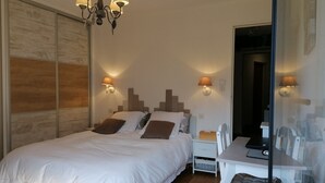 Un dormitorio con una cama grande, mesitas de noche, un escritorio y una silla.