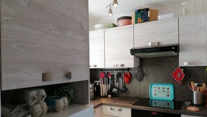 Una cocina moderna con armarios de madera clara, una campana extractora negra y un lavamanos de acero inoxidable.