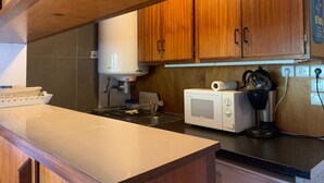 Een keuken met houten kasten, een witte kookplaat, een magnetron en een waterkoker.