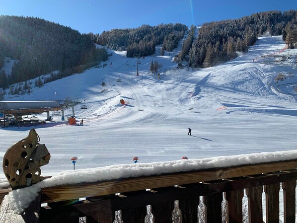 A ski slope with a chairlift, a ski lodge, and a wooden fence in the foreground.