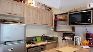 Una cocina moderna con armarios de madera, microondas integrado, refrigerador y encimera de madera.