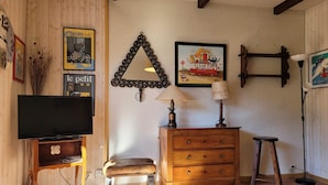Una sala de estar acogedora con televisor, muebles de madera y adornos en la pared.