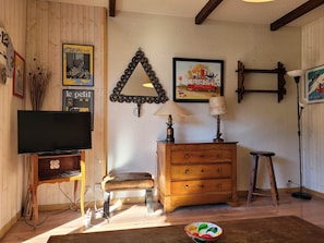 Uma sala de estar acolhedora com televisão, móveis de madeira e detalhes decorativos nas paredes.
