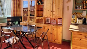 Een knus interieur met een houten kast, een glazen tafel en stoelen.