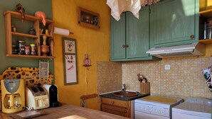 Een keuken met houten kastjes, een koffiezetapparaat, een broodrooster en een spoelbak.
